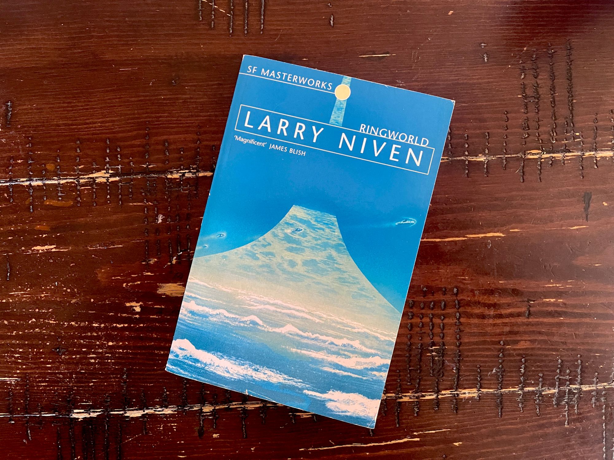 A copy of Larry Niven’s Ringworld book with a blue cover and a strip of a world stretching out from the bottom of the book to the top.